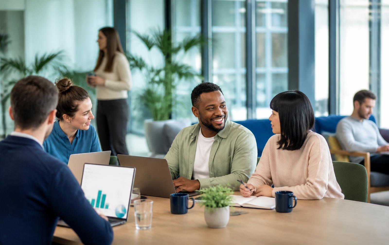 A diverse group of professionals collaborating around a laptop in a warm, modern coworking space